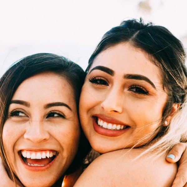 woman smiling beside topless woman